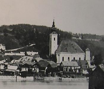 Die frühere St. Nikolauskirche, ein imposanter Rokokobau, 1769-70 errichtet, der westliche Glockenturm stammte im Kern aus der Romanik - (südlich:) rechts der noch heute erhaltene Wasserturm - Nach einem Brand 1769 in Oberndorf wurde die Pfarrkirche St. Nikolaus vom Trostberger Maurermeister Franz Alois Mayr (deutscher Kirchenbaumeister; Trostberger Rokokomeister, Oberbayern) und dessen Schwiegersohn Franz Joseph Lindmayr neu aufgebaut und vom Chiemseer Bischof Sigmund Christoph von Waldburg zu Zeil und Trauchburg 1798 geweiht - Hier wurde am 24. Dezember 1818 erstmals 'Stille Nacht' gesungen - Foto: Wikimedia Commons - Gemeinfrei
