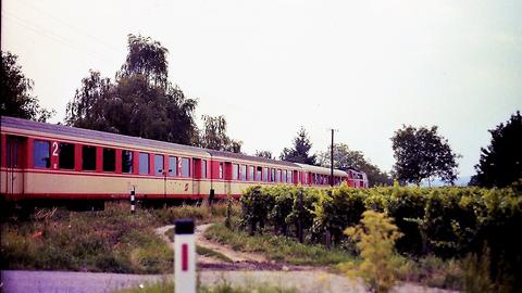 Nebenbahn der Westbahn. Eisenbahnkreuzung zwischen Lambach und Wels (Sommer 1989). Vier Schlierenwagen in rot-weißer Farbgebung und eine rote Diesellok der Baureihe 2143 Nebenbahn der Westbahn. Eisenbahnkreuzung zwischen Lambach und Wels (Sommer 1989). Vier Schlierenwagen in rot-weißer Farbgebung und eine rote Diesellok der Baureihe 2143
