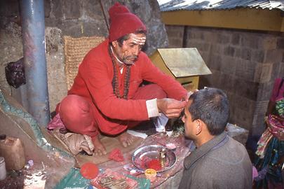 A Brahmin makes a red sign of blessing on the forehead of a pilgrim. His own forehead painting indicates that he is a follower of Shiva A Brahmin makes a red sign of blessing on the forehead of a pilgrim. His own forehead painting indicates that he is a follower of Shiva