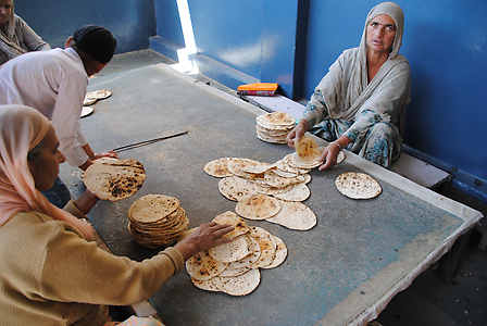 Women lay flatbread on top of each other for distribution Women lay flatbread on top of each other for distribution